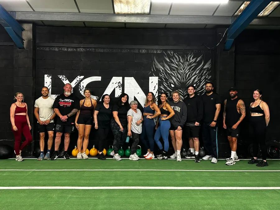 Lycan Strength members lined up in front of the Lycan wall on the turf