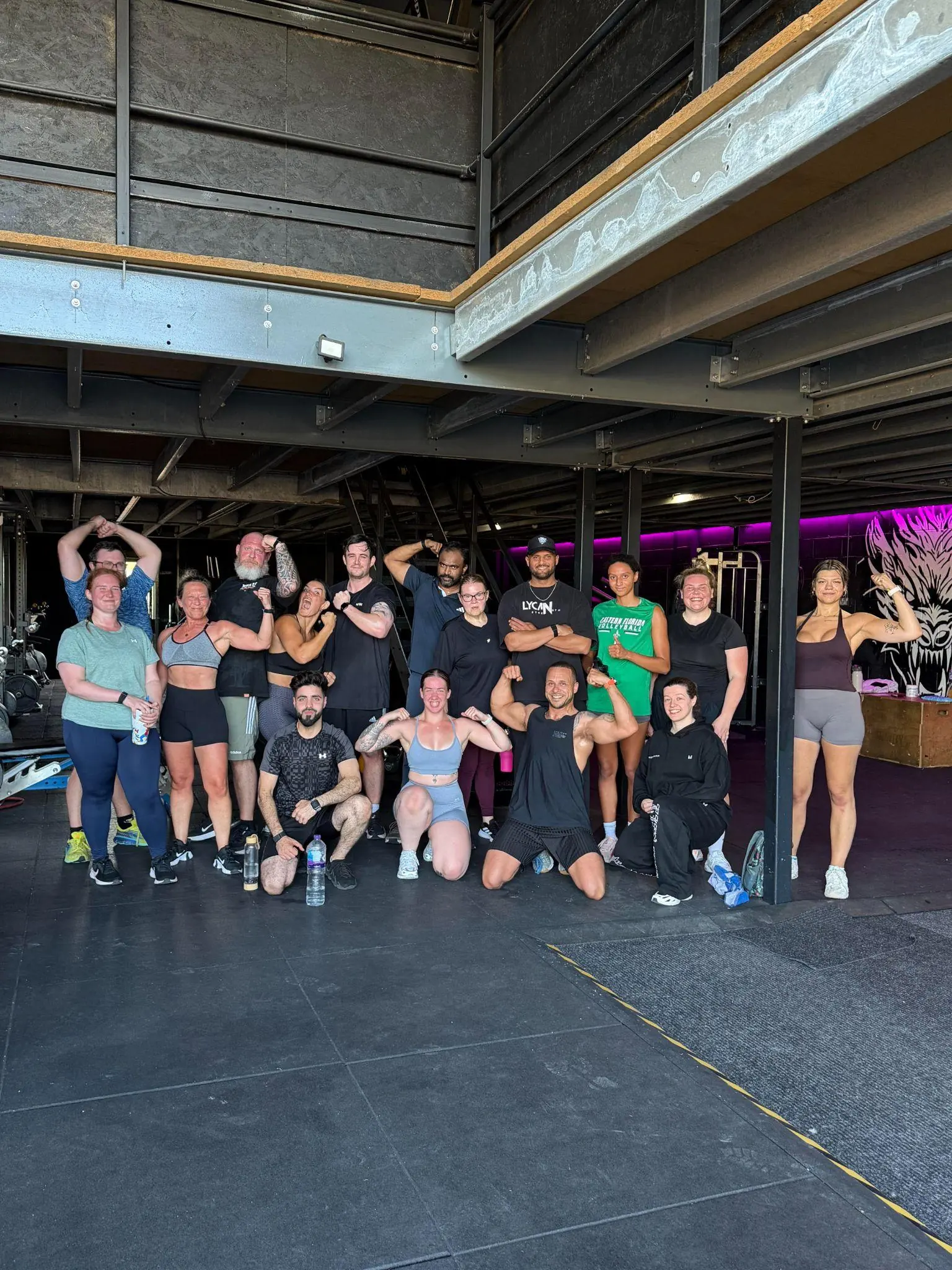 Members flexing for a group photo under the mezzanine