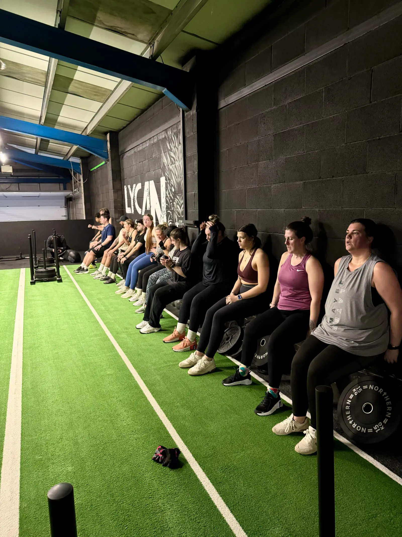 A row of members holding a wall sit along the turf